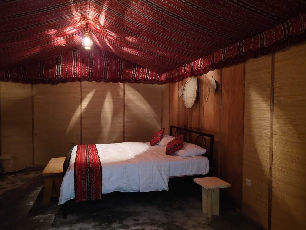 A wooden room with a bed, a small table, and a wall-mounted hat.