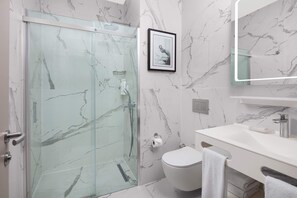 A modern bathroom with a glass-enclosed shower, a toilet, and a sink with a mirror above it. - Delta Hotels by Marriott Istanbul Kagithane (Istanbul)