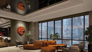 Um hall amplo com um sofá modular grande, área de refeições e janelas enormes com vista para a cidade.