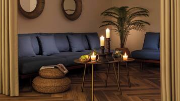A living room with a dark blue sofa, two round mirrors on the wall, a potted plant, a small round table with candles, and wicker baskets on the floor.