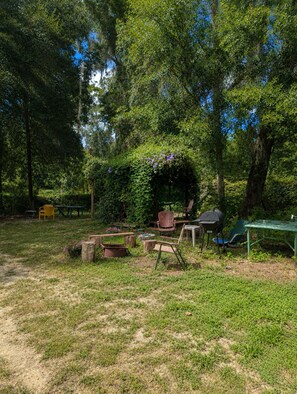 Een terras met een rustieke houten tafel, stoelen en een barbecue.