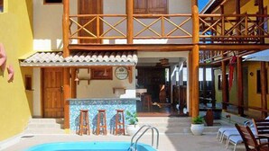 Un edificio de dos pisos con piscina, mobiliario exterior y un patio cubierto.
