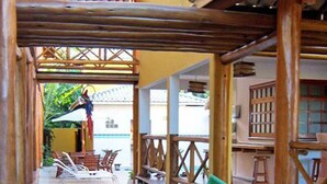 Una terraza de madera con piscina, sillones de descanso y una cascada pequeña.