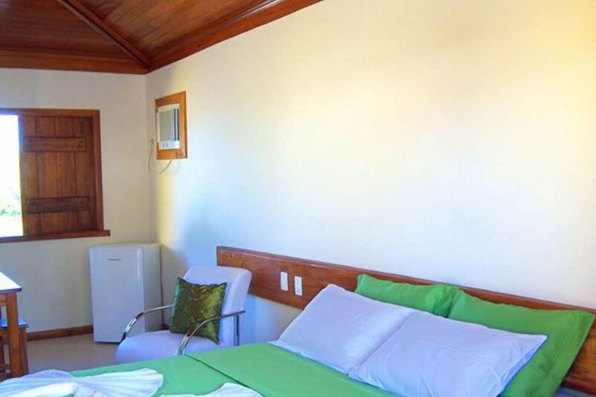A bedroom with a bed, a small desk, and a window.
