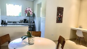 Une cuisine moderne avec des meubles blancs, une table à manger avec des chaises et une orchidée en pot.