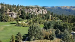 Un campo de golf con un risco rocoso y un bosque denso.