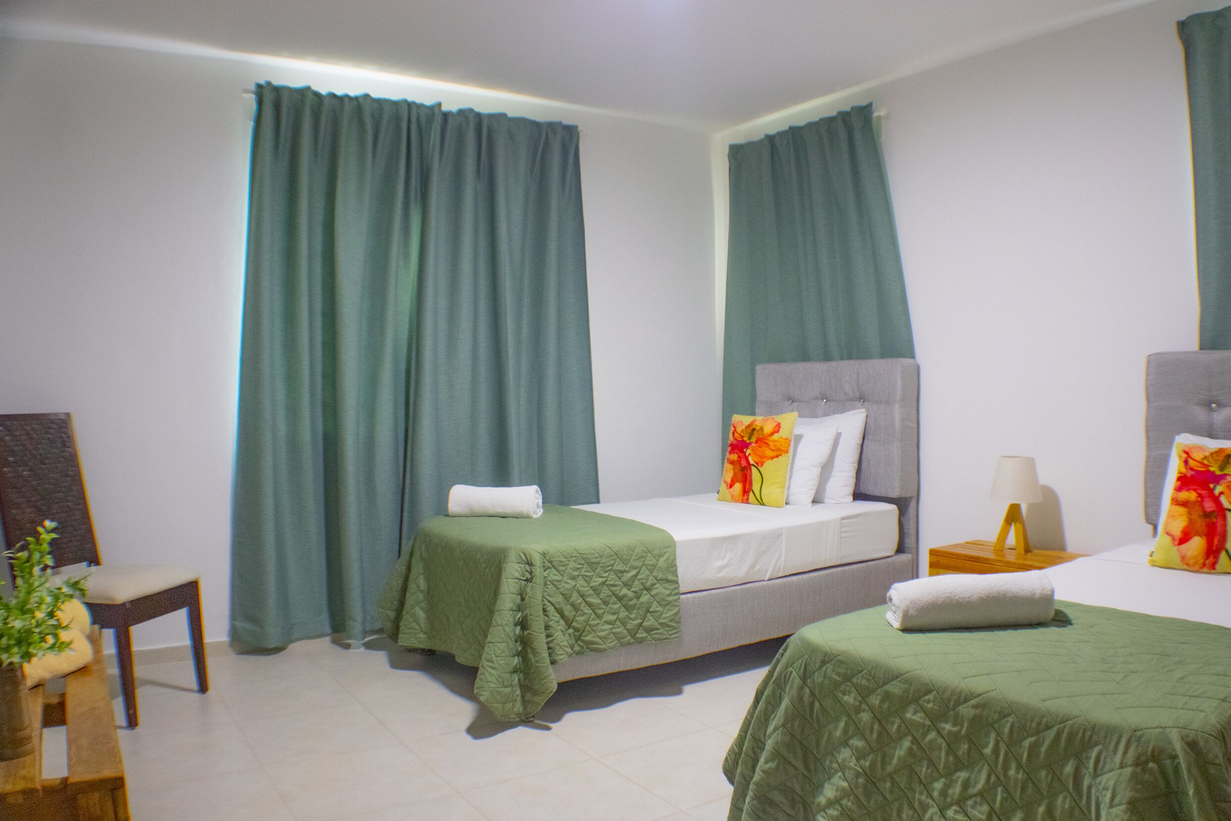 Quarto de hotel com duas camas de solteiro, uma escrivaninha e uma cadeira.