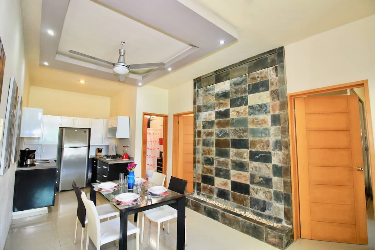 A modern kitchen with a refrigerator, stove, and dining area with a table set for two.