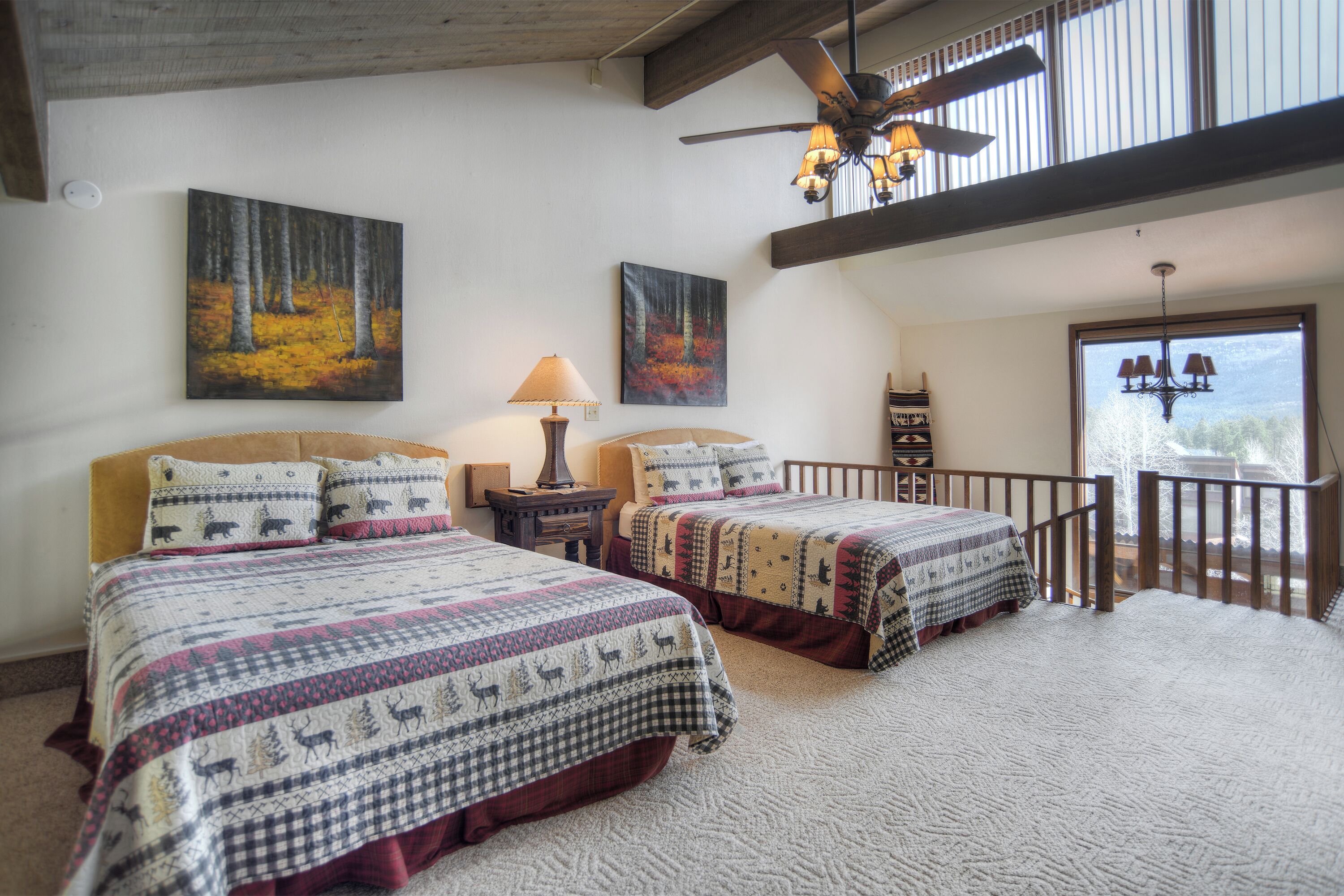 A bedroom with two beds, a ceiling fan, and artwork on the walls.