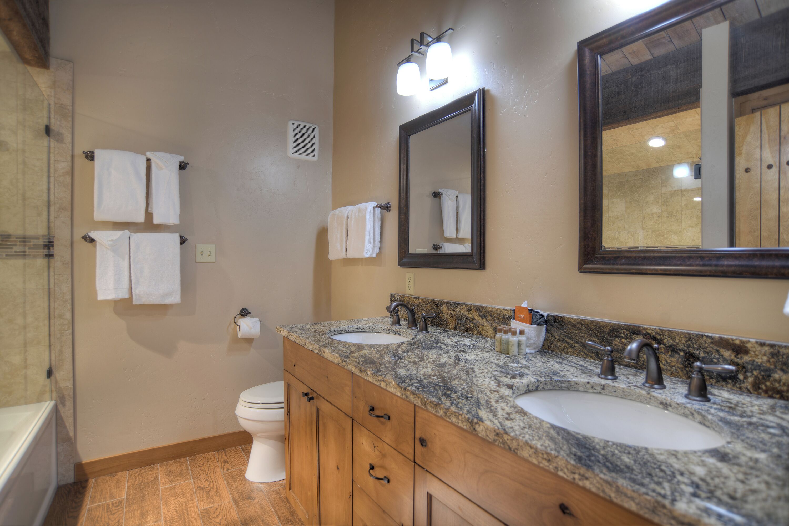 A bathroom with two sinks, a toilet, and a large mirror.