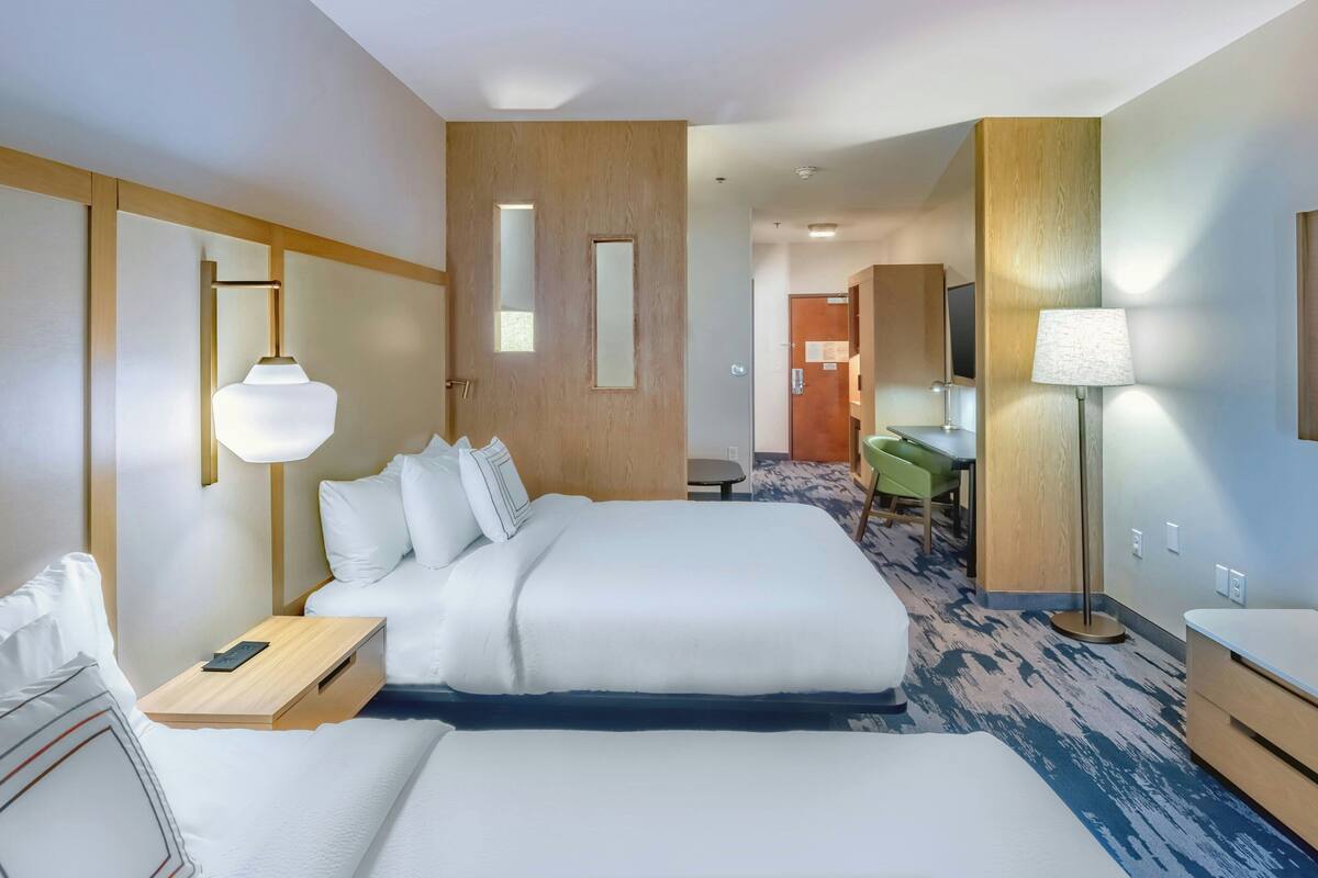 Une chambre d’hôtel avec un grand lit, des tables de chevet, un bureau et une chaise.
