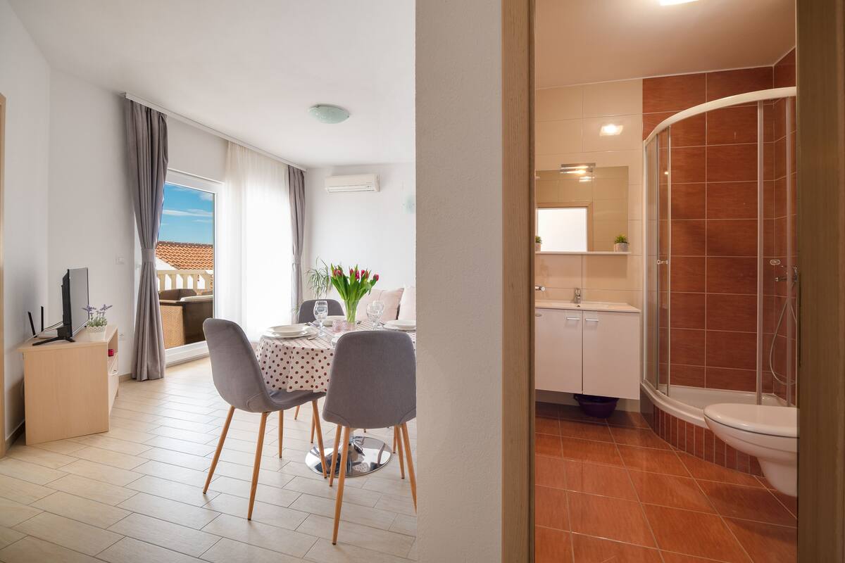A modern hotel room with a dining area, a shower, and a view of the outside.
