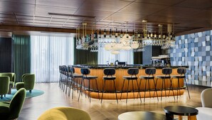 Un espace bar moderne doté d’un bar central, de nombreux espaces pour s’asseoir et d’un mur orné de motifs.