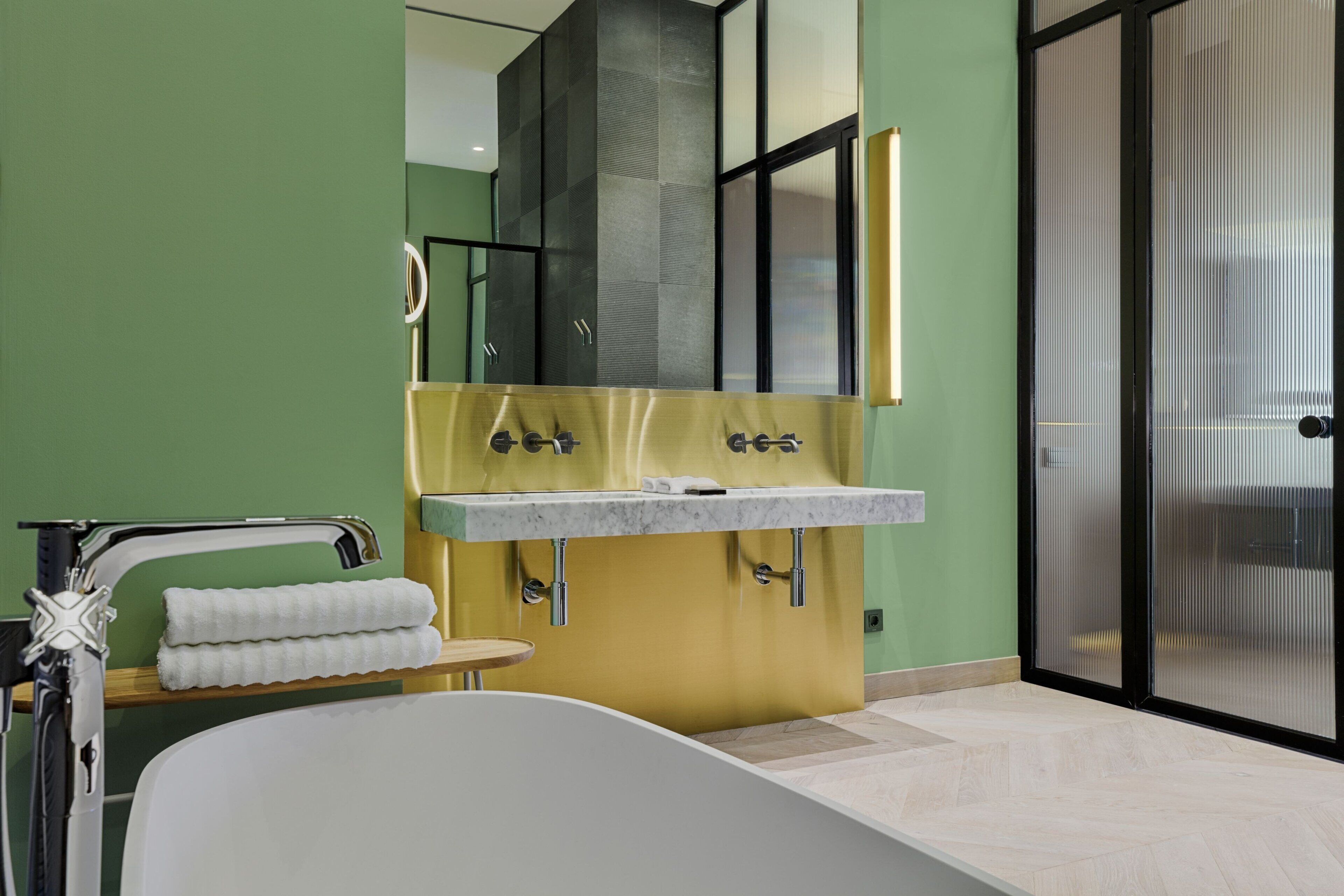 A modern bathroom with a bathtub, dual sinks, and a large mirror.