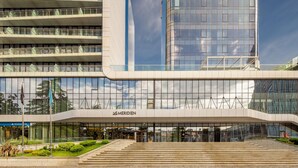 Un bâtiment moderne doté d’une façade en verre, d’une entrée imposante avec des marches et d’une enseigne indiquant « MERIDEN ».