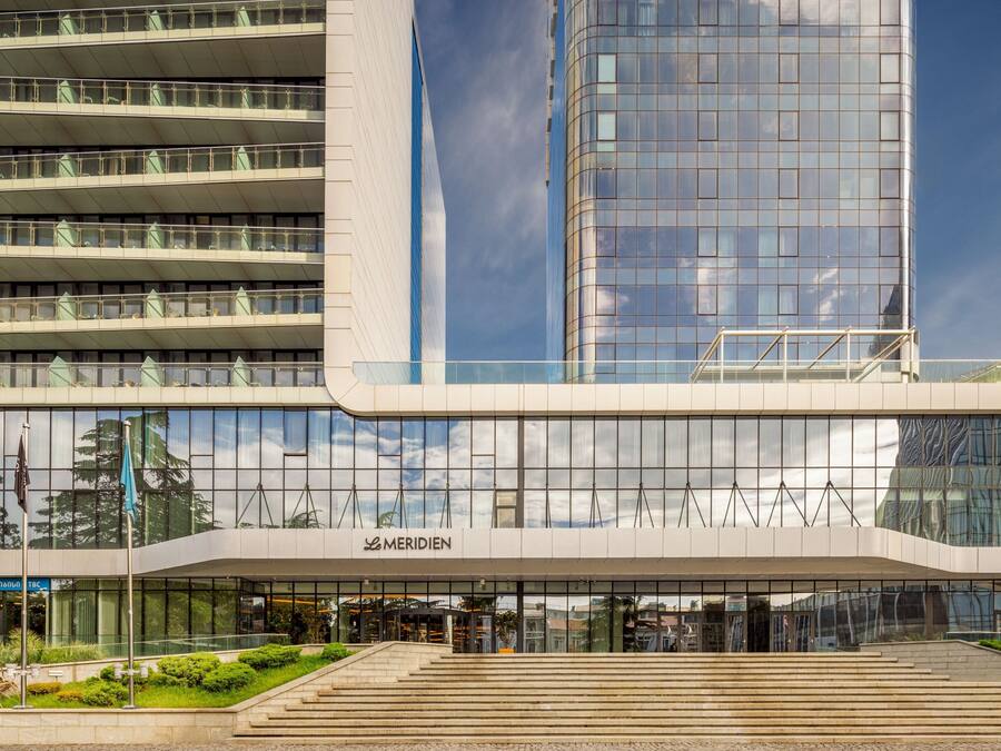 A modern building with a glass facade, a prominent entrance with steps, and a sign reading "MERIDEN".