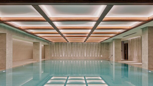 Une piscine intérieure moderne, dotée d’un carrelage aux motifs géométriques, d’un éclairage encastré et d’un design épuré et minimaliste.