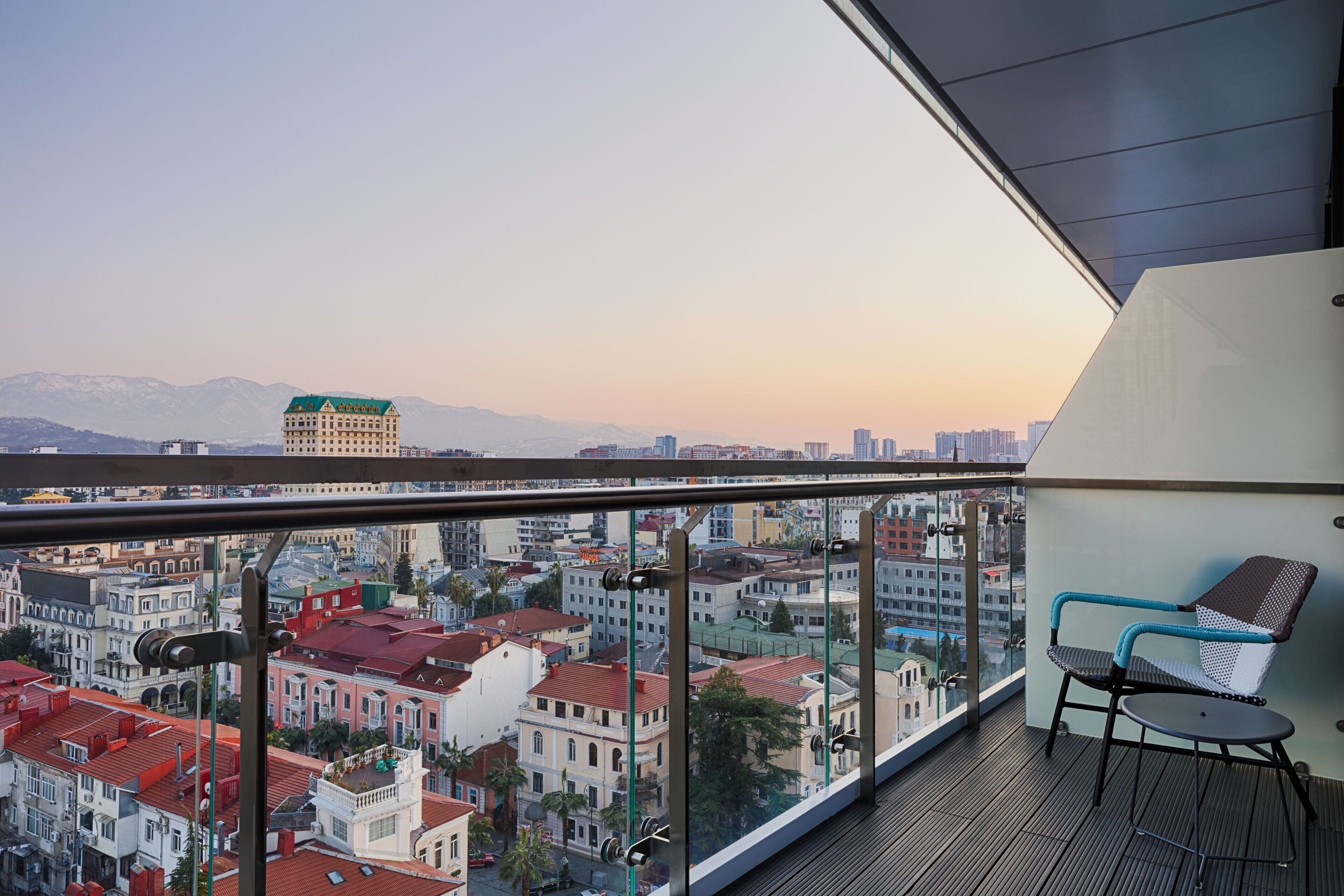 Un balcón con vistas a un paisaje urbano, que incluye edificios y montañas.