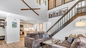 A spacious living area with a gray sofa, a coffee table, and a staircase with wooden railings.