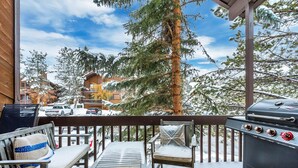 A covered outdoor seating area with a grill, wooden deck, and snow-covered surroundings.