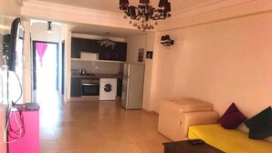 A living room with a sofa, a coffee table, and a kitchen in the background. - Beautiful apartment in Residence with Swimming pool 4624 (Marrakech)