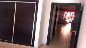 A hallway with a sliding door leading to a room with a bed and a window with red curtains. - Beautiful apartment in Residence with Swimming pool 4624 (Marrakech)