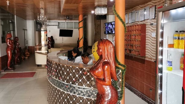 A reception area with a counter, a television mounted on the wall, and a refrigerator stocked with beverages. - Gran hotel Jungla (Iquitos)