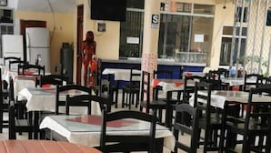 A cafeteria with multiple tables and chairs, a statue, and a vending machine. - Gran hotel Jungla (Iquitos)