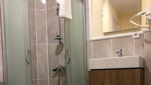 Ein modernes Badezimmer mit einer Duschkabine, einer weißen Toilette und einem Holzbadezimmer-Möbel mit Waschbecken.