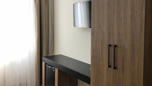 Ein Zimmer mit Holzschrank, integriertem Fernseher und einem fenster mit Vorhängen.