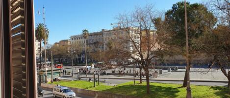 A street view with a building, cars, and a park area.