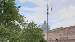 A street view with a car, a lamp post, and a building with a dome in the background. - Stefano House Roma (Rome)