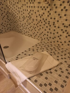 A bathroom with a tiled shower area and a towel with 'SLIPPERS' written on it. - Stefano House Roma (Rome)