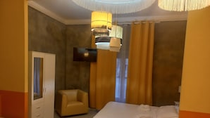 A hotel room with two beds, a sofa, a TV, and a wardrobe. - Stefano House Roma (Rome)