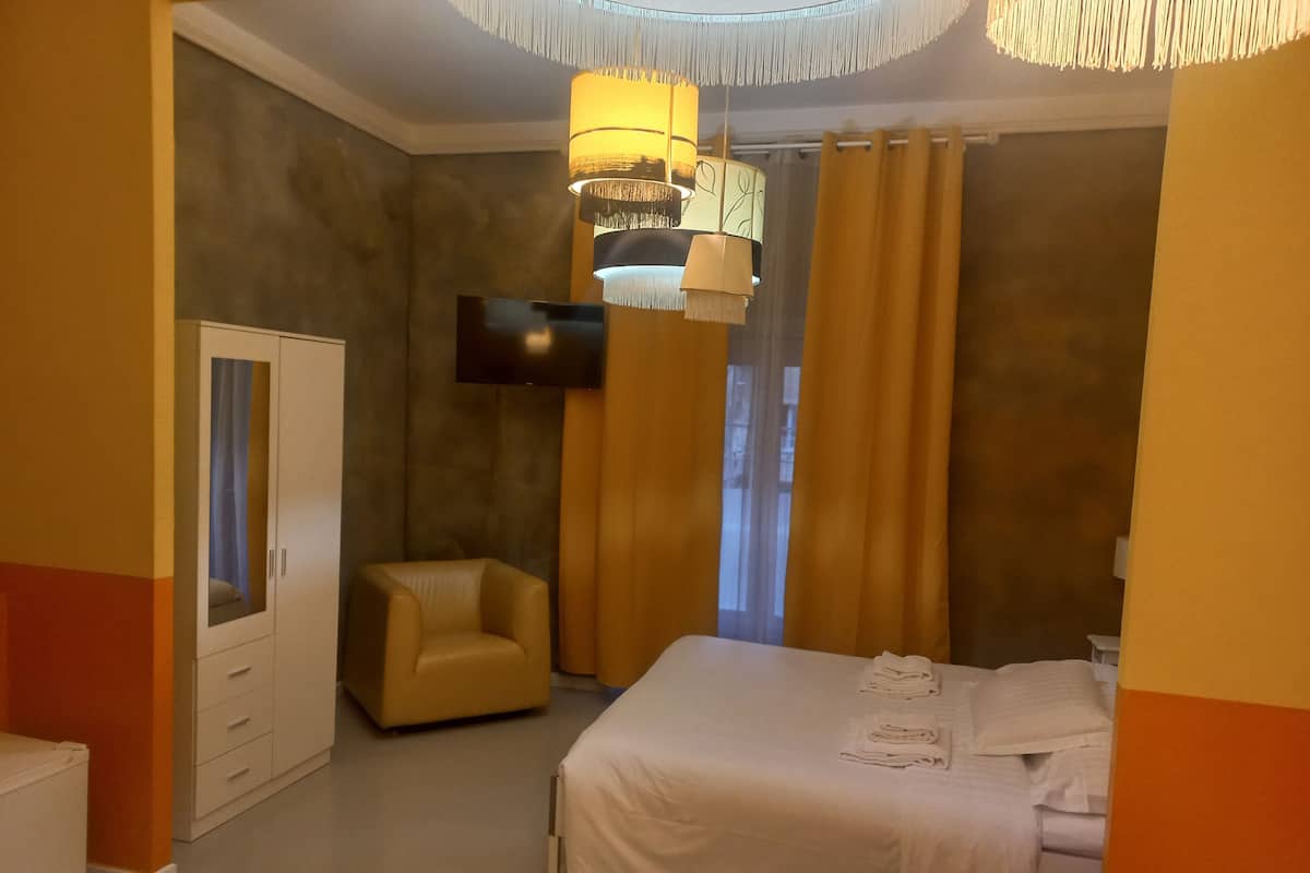 A hotel room with two beds, a sofa, a TV, and a wardrobe.