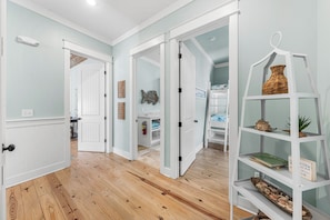 A hallway with wooden flooring, white doors, and a white shelving unit with decorative items.