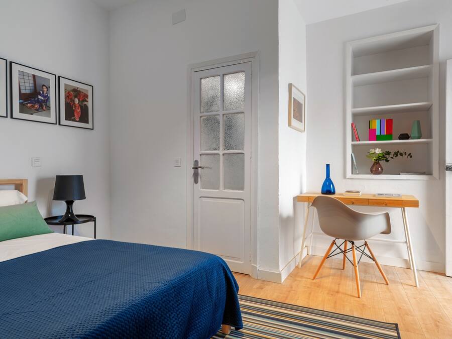 A bedroom with a bed, a desk, a chair, and a bookshelf.