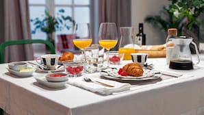 A breakfast table set with croissants, fruit, and beverages, including orange juice and coffee. - Art Suites by Casa de Indias (El Puerto de Santa Maria)