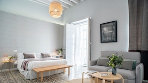 A modern bedroom with a bed, bench, and a grey sofa. - Art Suites by Casa de Indias (El Puerto de Santa Maria)