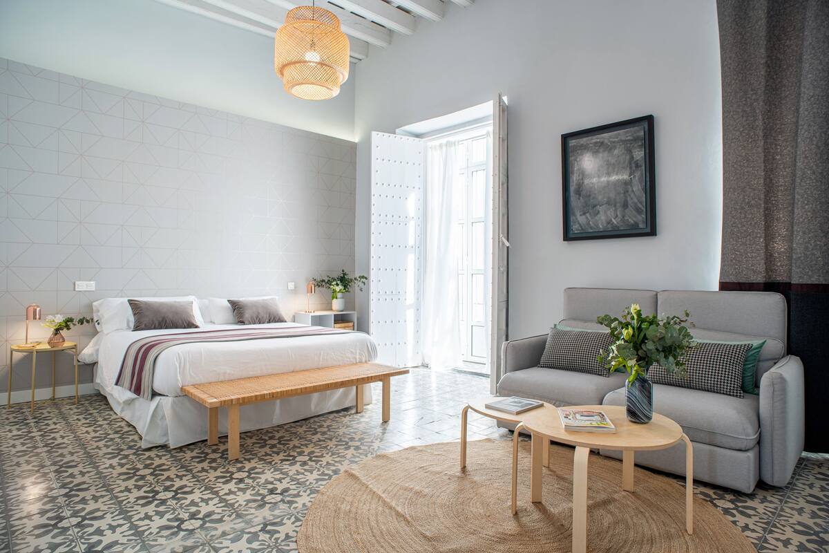 Une chambre à coucher moderne avec un lit, un banc et un canapé gris.