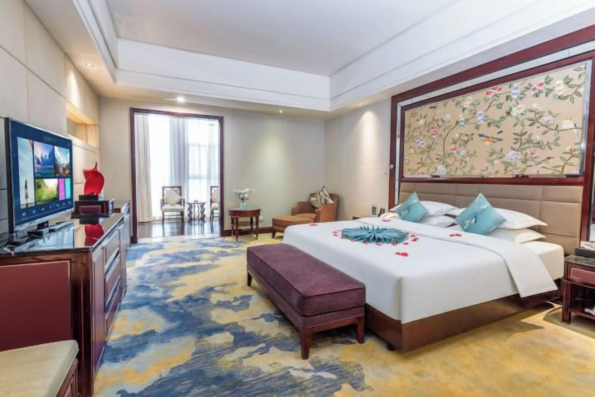 Una camera d'albergo con un letto grande, una televisione, una scrivania con un computer e vista all'esterno.