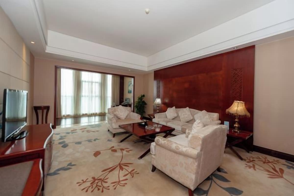 A hotel living room with a sofa set, a coffee table, and a TV.