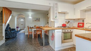 Une cuisine moderne avec des meubles blancs, une table à manger en bois et un four encastré.