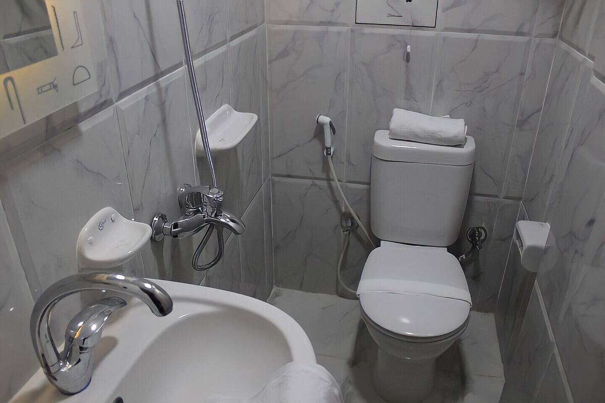 Ein kleines Badezimmer mit einem weißen Waschbecken, einer Dusche und einer Toilette.