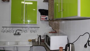 A kitchen with a white sink, a microwave, and a kettle. There are green cabinets above the sink and a green backsplash. - Sunset Hotel Cairo - Hostel (Cairo)