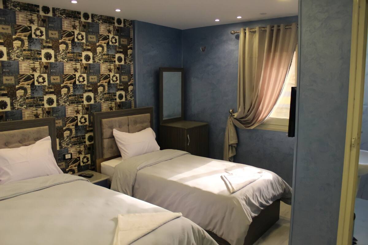 Ein Hotelzimmer mit zwei Betten, einem großen Spiegel und einer Wand mit Muster.
