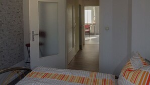 Ett hotellrum med en säng, en stol, en dörr som leder till ett annat rum och en hall.