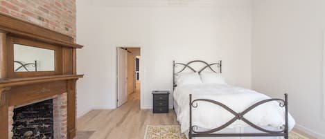 Een slaapkamer met een bed, een open haard, een spiegel en een kroonluchter.