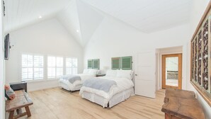 A spacious bedroom with two beds, a wooden bench, and a door leading outside. - Benson Guest House (Uvalde)