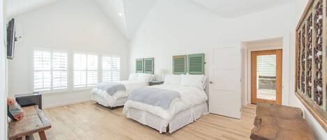 A spacious bedroom with two beds, a wooden bench, and a door leading outside.